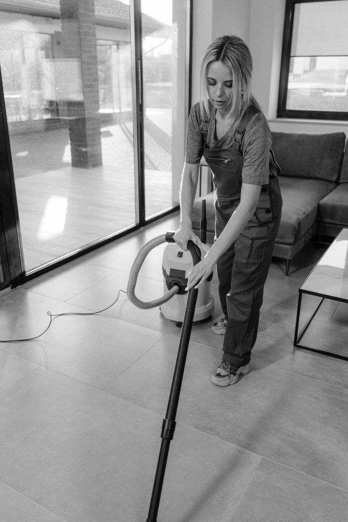 pexels photo 6195287 6195287 A woman in work clothes vacuuming indoors, emphasizing cleanliness and efficiency.